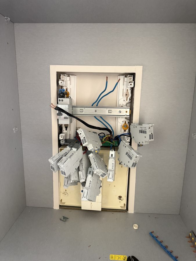 Remplacement d'un tableau électrique en cours : anciens disjoncteurs déposés, rail et câblage neufs