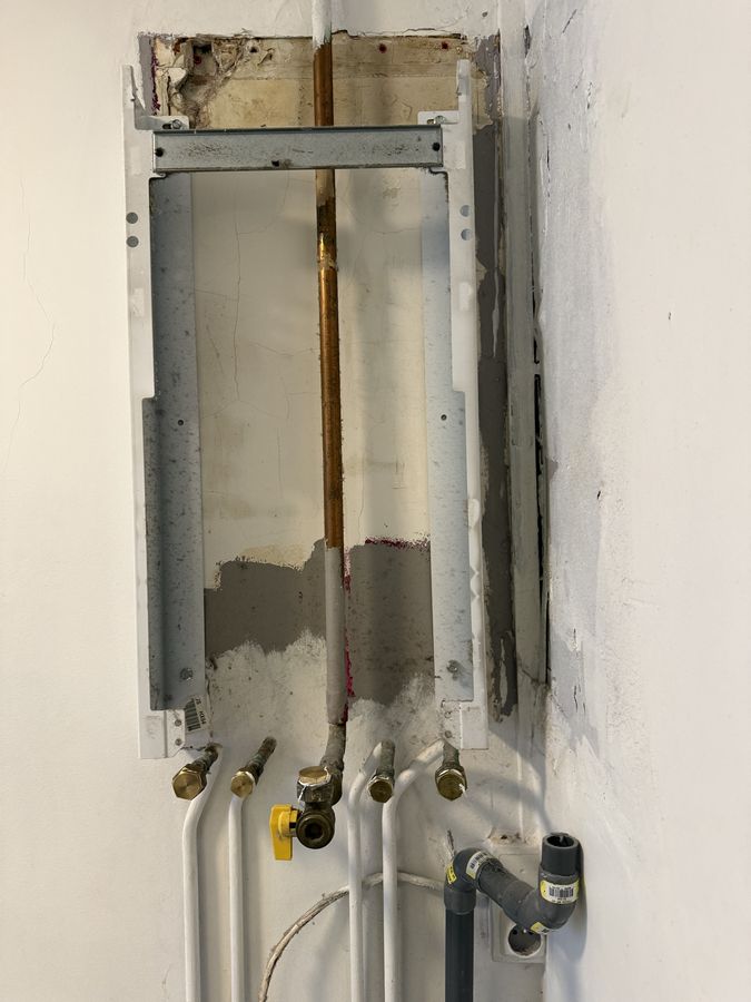 Barrette de raccordement d'une chaudière murale : arrivées d'eau, robinet gaz, évacuation PVC