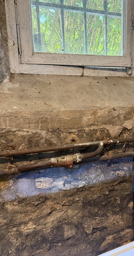 Ancien réseau en cuivre avec vanne d'arrêt sur un mur en pierre, avant reprise